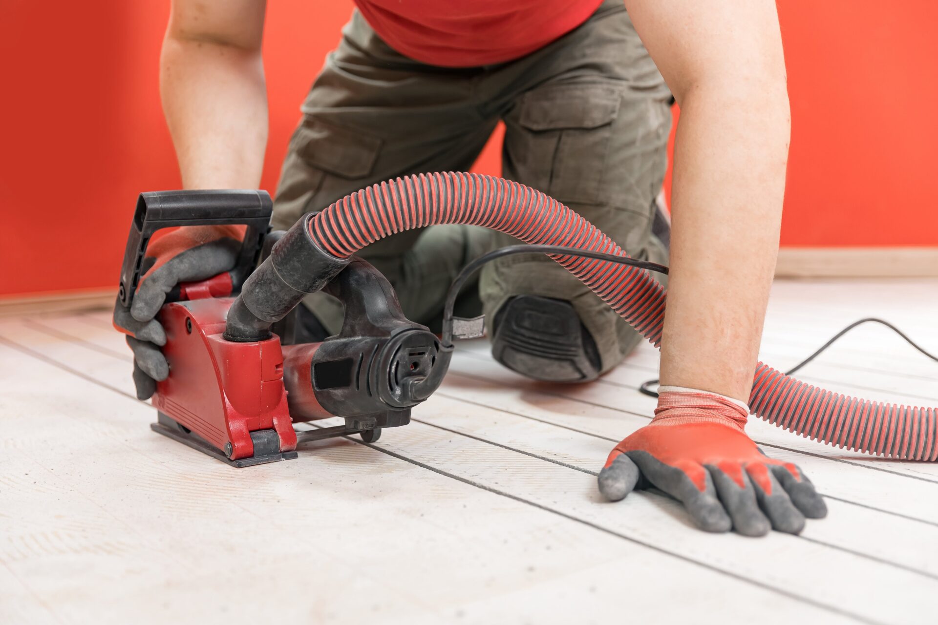 Construction worker cuts concrete floor for electrical cable, builder uses circular saw with diamond crown. Install underfloor heating.