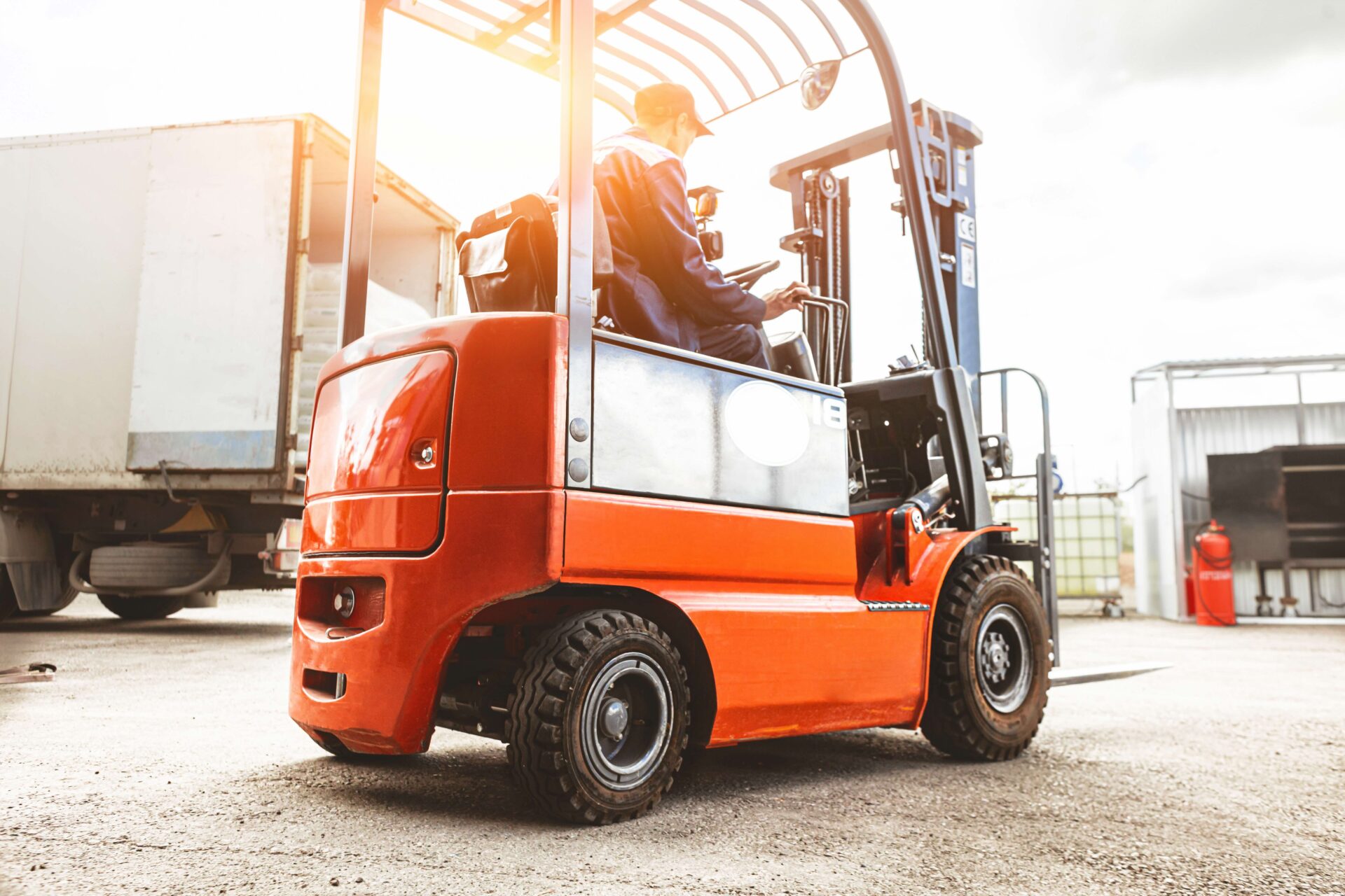 A man on a forklift works in a large warehouse, unloads bags of raw materials.